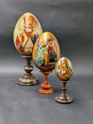trois œufs décoratifs ornés de motifs religieux, posés sur une table