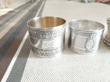 three silver cups sitting on a table with a striped tablecloth
