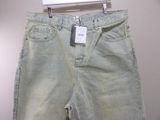 denim pants with a white tag on a hanger on a wall