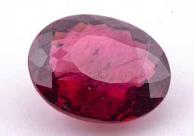 un gros plan d'une pierre précieuse ovale rouge sur une surface blanche