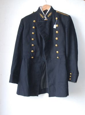 an old military jacket hanging on a wall next to a wooden hanger