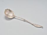 une cuillère en argent posée sur une surface blanche, avec une autre cuillère en argent dessus