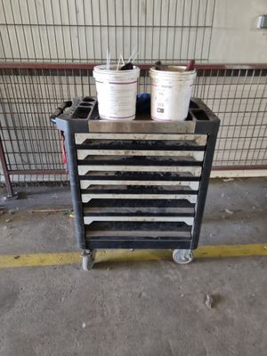 several buckets of paint are stacked on a cart in a garage
