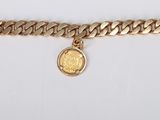 a close up of a gold chain bracelet with a coin on it