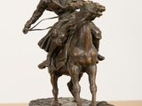 statue of a man riding a horse with a lasset on his back