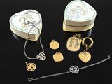 two heart shaped jewelry boxes and a chain on a black surface