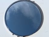 a round mirror on a white wall with a sky in the background