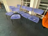 four blue chairs are lined up in a row in a room