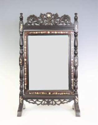un miroir richement sculpté repose sur un socle, se détachant sur un fond blanc
