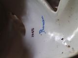 a white porcelain heart shaped object with blue writing on it