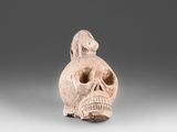 a close up of a clay figurine of a skull with a bird on its head