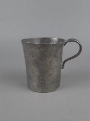 une coupe en argent munie d'une anse, sur fond gris