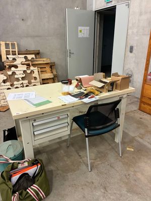 une table avec une chaise et un sac posé dessus, dans une pièce