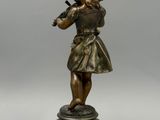 statue en bronze représentant une jeune fille jouant du violon, posée sur un socle