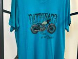Le t-shirt est bleu et il y a une moto dessus.
