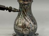 a silver tea pot with a wooden handle on a table