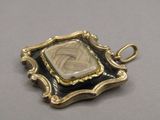 an image of a gold and black pendant with a stone in the center