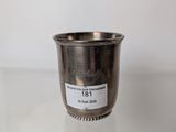 a silver cup sitting on top of a glass table next to a white wall