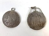 two silver coins are sitting next to each other on a white surface