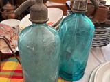 deux bouteilles en verre bleues posées sur une table recouverte d'une nappe rouge et jaune