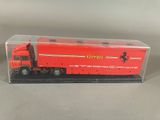 un camion Ferrari rouge dans une boîte transparente posée sur une surface grise