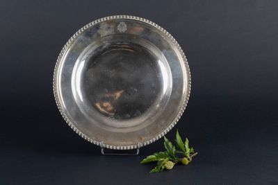 an antique silver plate with a flower on a black background