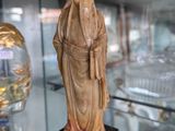 une statue représentant un homme debout sur un piédestal devant une vitrine