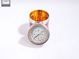 a clock sitting in a glass container on a white surface