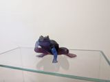 figurine de grenouille violette posée sur une étagère en verre