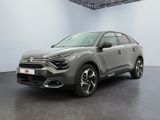 Une voiture grise est garée dans une grande pièce au sol noir.