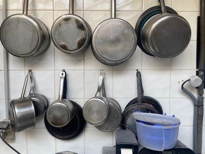 casseroles et poêles suspendues au mur d'une cuisine
