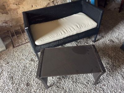 a black wicker chair with a white cushion next to a coffee table