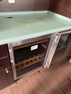 a green counter top with a wine cooler underneath it
