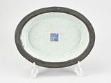 a white plate with a black rim on a stand