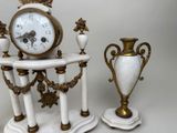 two white and gold vases and a clock on a table