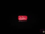 un diamant rouge sur une surface noire dans l'obscurité