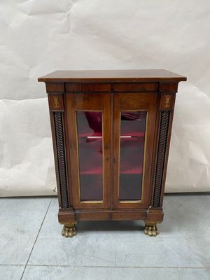 une vieille armoire en bois avec une porte vitrée et une chaise rouge