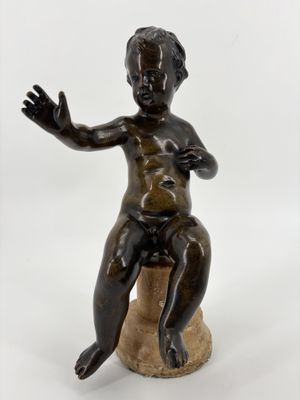 statue en bronze représentant un garçon assis sur un rocher, les mains tendues