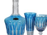 three blue wine glasses and a decanter on a white background