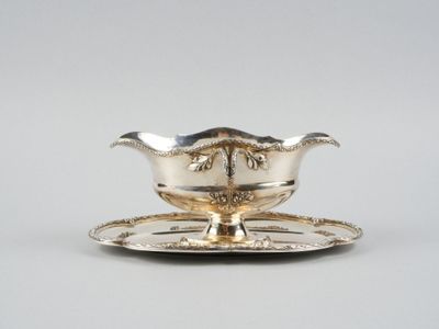 un service en argent ancien composé d'une assiette et d'une soucoupe posée dessus