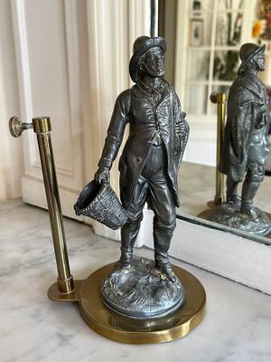 a bronze statue of a man holding a hat and a bag