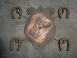 une plaque métallique sur laquelle figurent un cheval et des fers à cheval