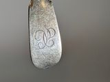 a silver spoon with a monogram on it hanging from a hook