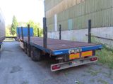 un camion à plateau garé devant un immeuble