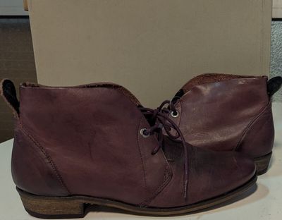 des bottes en cuir bordeaux avec des lacets, posées sur une table