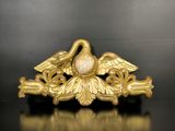 une image représentant une broche en forme d'oiseau en or posée sur un fond noir