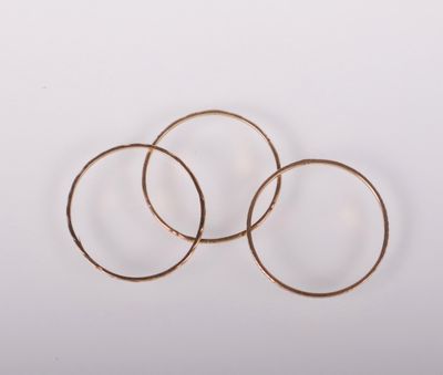 trois boucles d'oreilles en anneau dorées sur fond blanc