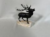 figurine représentant un cerf aux bois imposants, debout sur un rocher