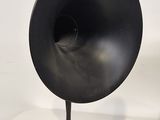 a black speaker on a metal stand on a white surface