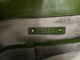 someone is holding a green purse with a name tag on it